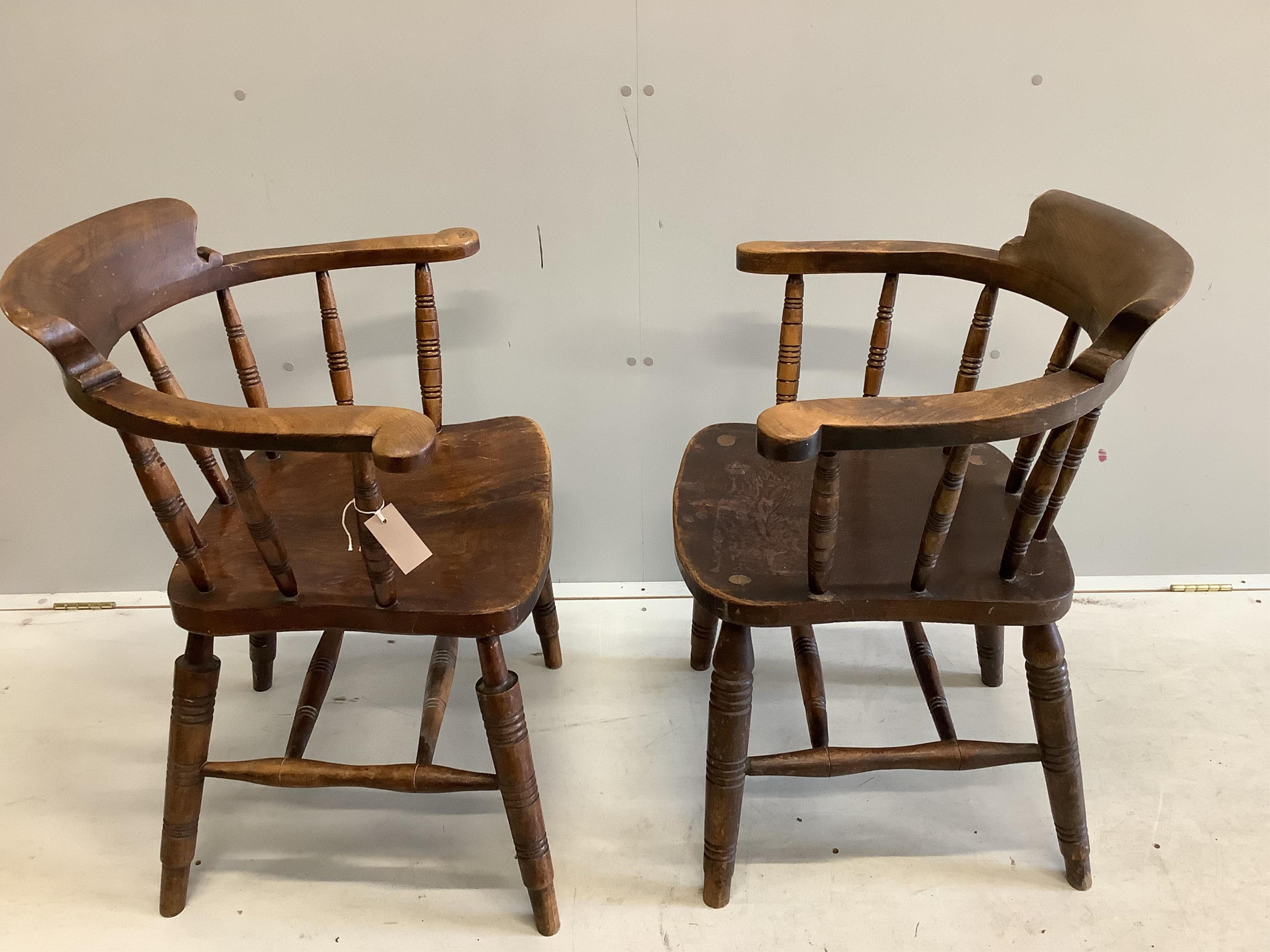 A pair of early 20th century elm and beech smokers bow chairs by Glenister, Wycombe, one bears Edward VII cypher, width 59cm, depth 48cm, height 84cm. Condition fair, one seat has cushion foam residue, the other split ve